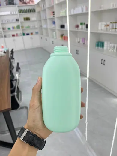 Chai nhựa màu xanh mint dáng dẹt cầm trên tay